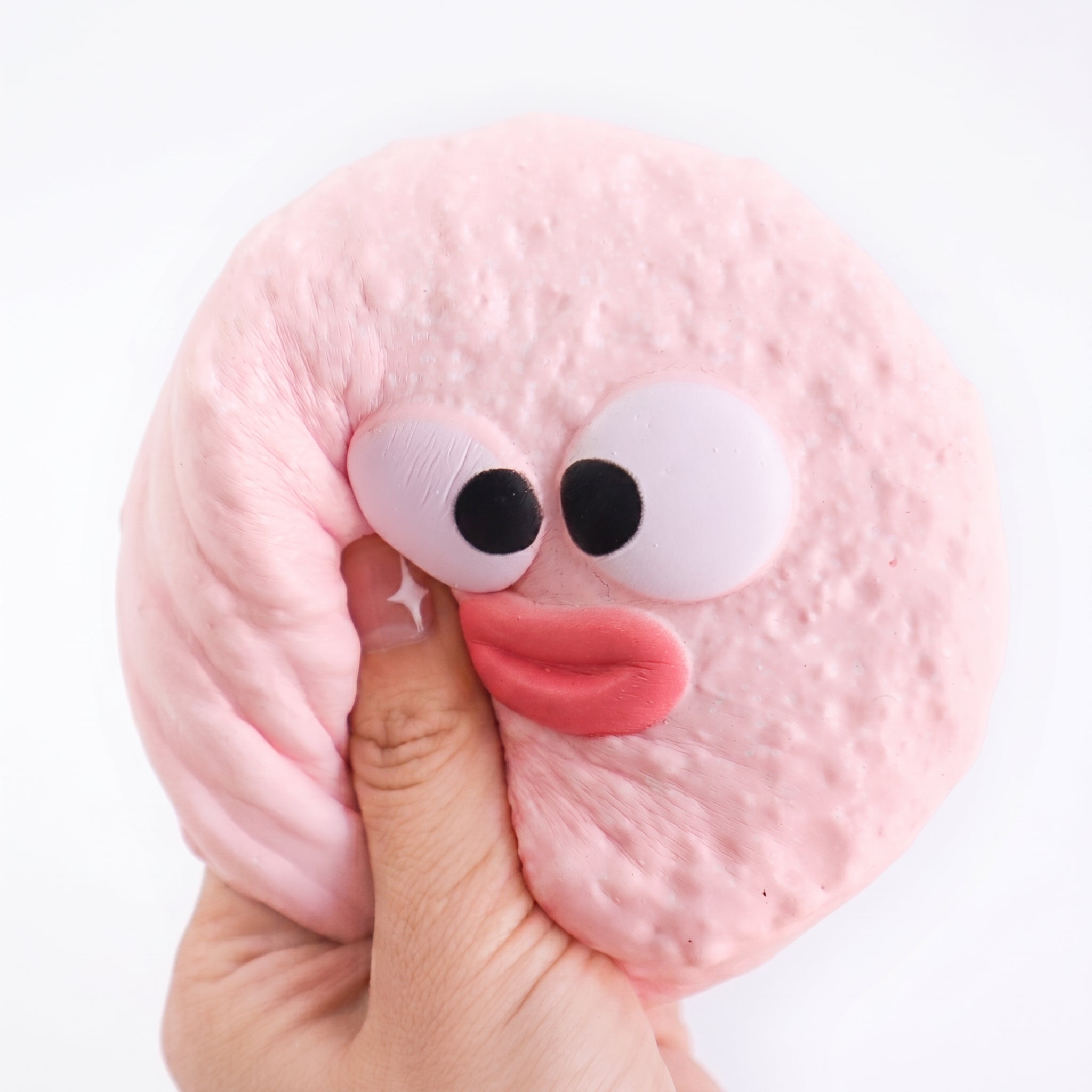 A hand pressing Pouty Puff